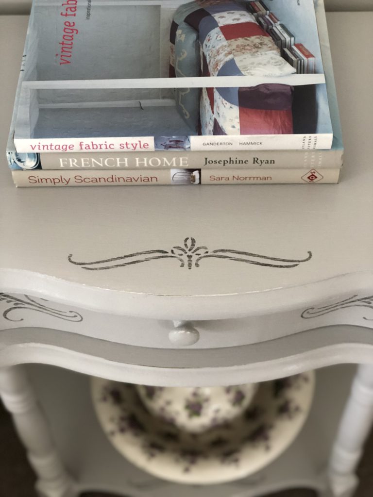 stencilled Bedside table top with books and faded jug and bowl