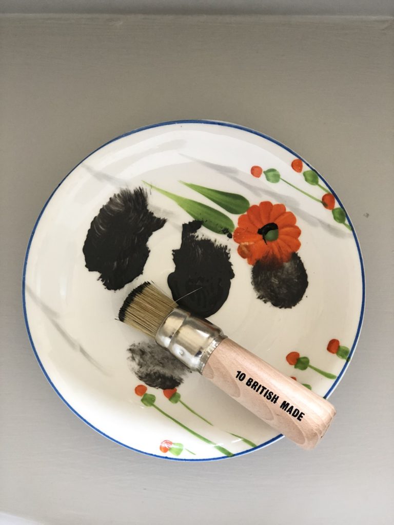 stencil brush and grey paint on orange floral tea plate