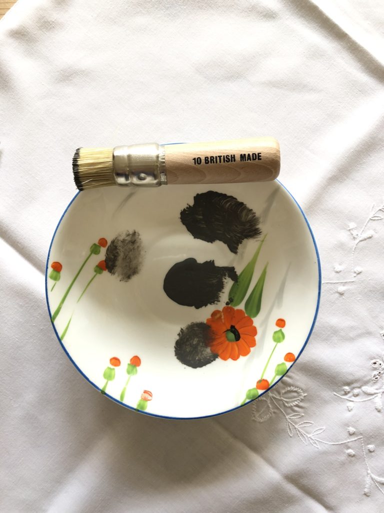 stencil brush and grey paint on orange floral tea plate