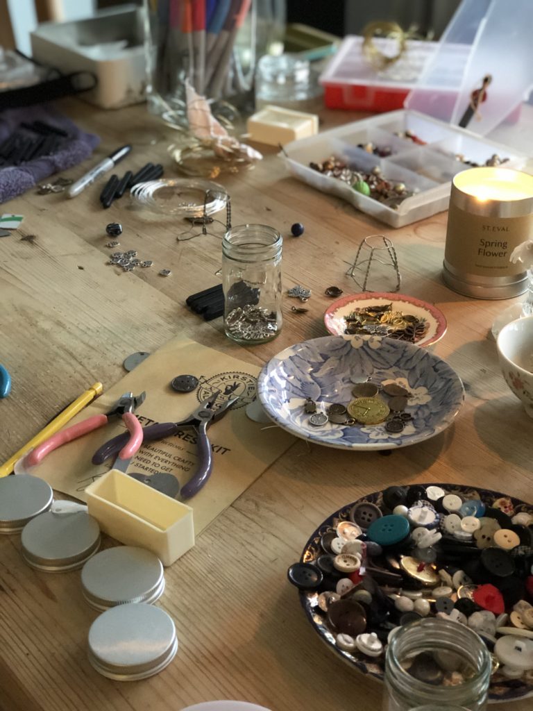 Busy craft table full of trinkets and buttons to make metal stampind decoration