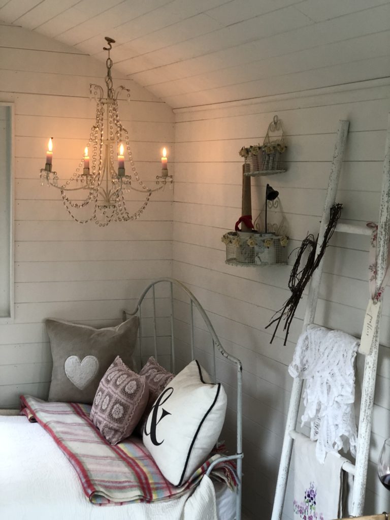 candle lit white chandelier above bed with cushions and vintage decor