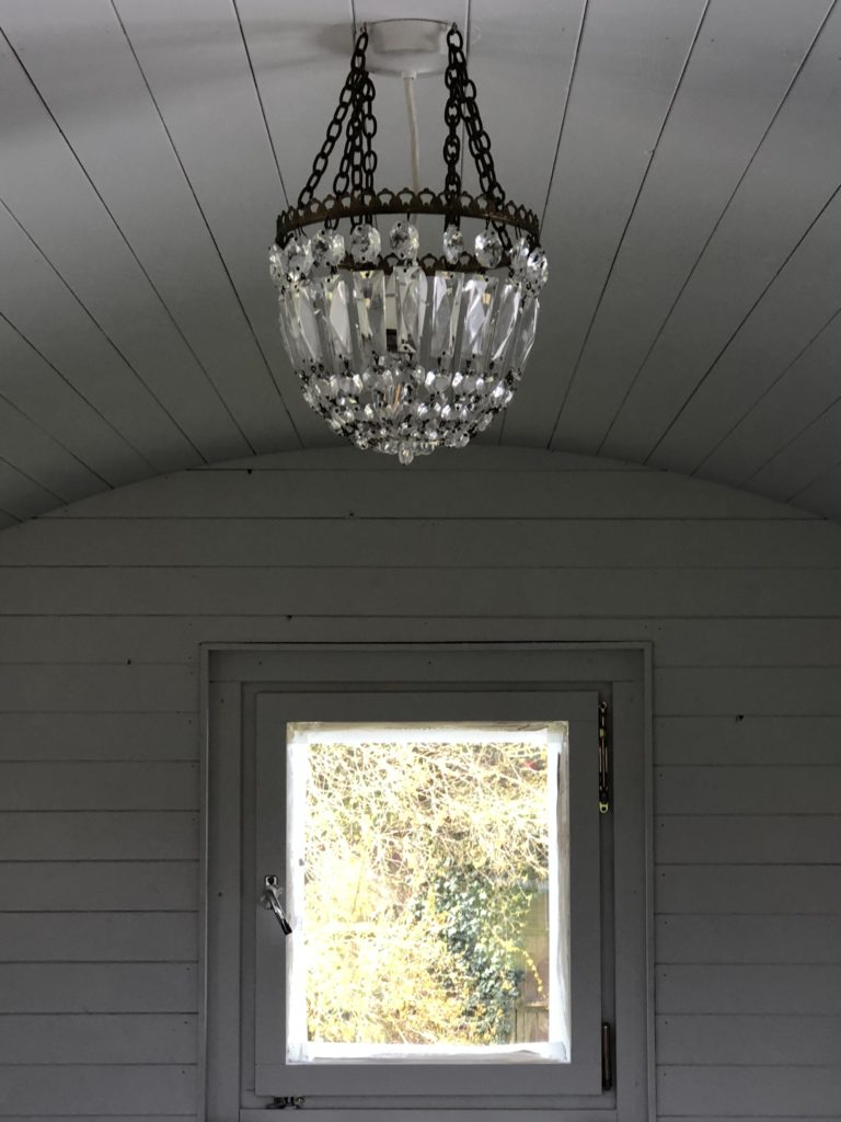 glass chandelier and window in white painted shepherd's hut