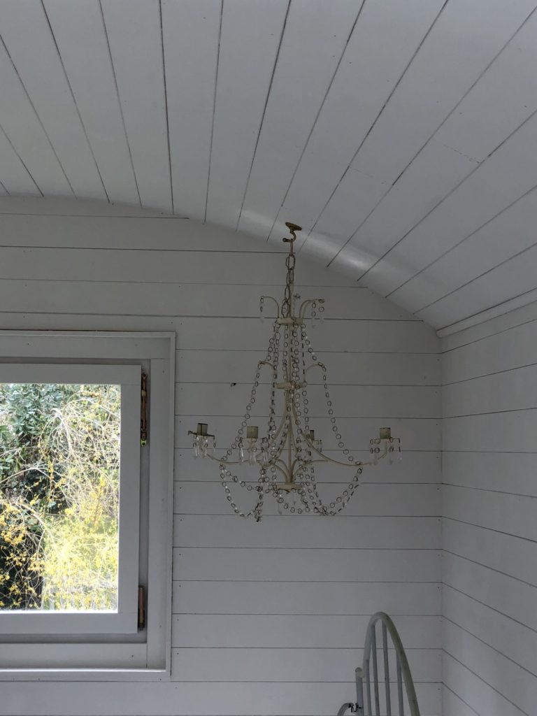 white candle chandelier in white painted shepherd's hut