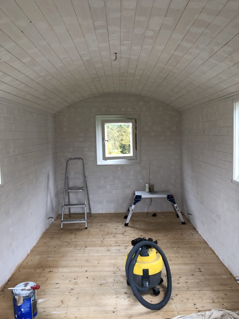 Painting a shepherds hut white with step ladders and yellow hoover