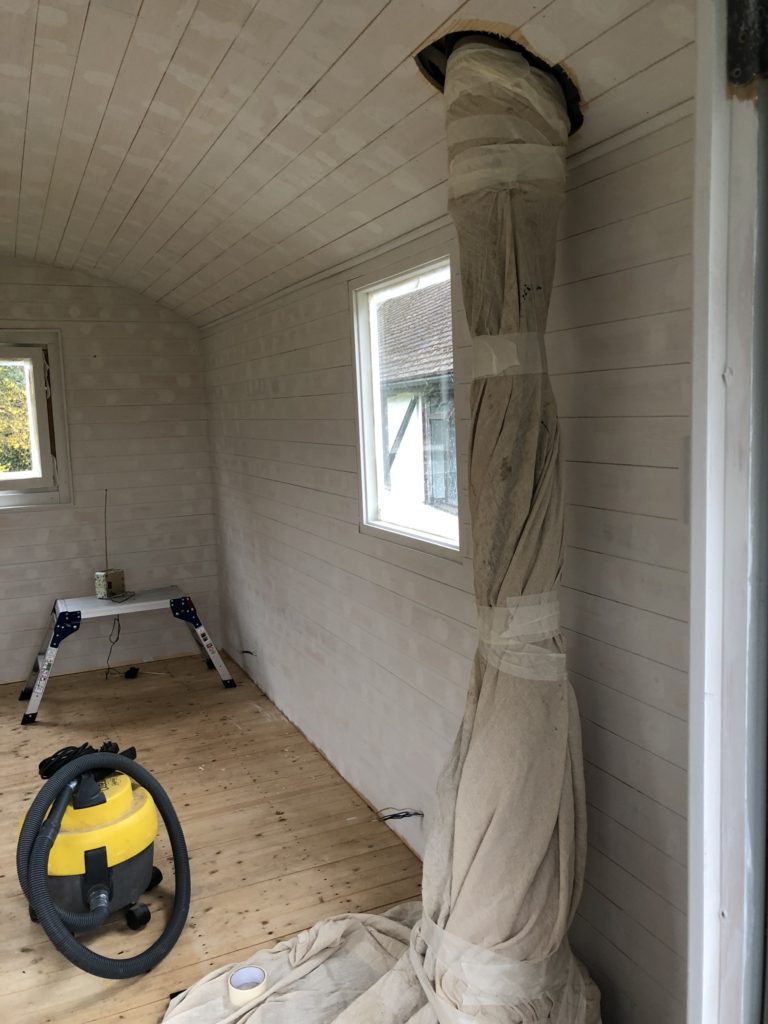 Painting a shepherds hut white with step ladders and yellow hoover