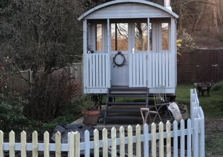 white picket fence surrounding potential small cottage garden in front of painted shepherds hut