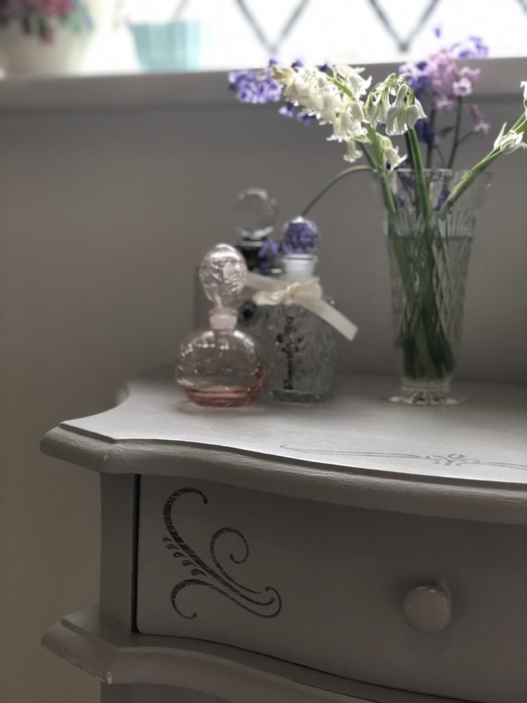 stenciled table, perfume bottles and flowers add to bathroom refresh