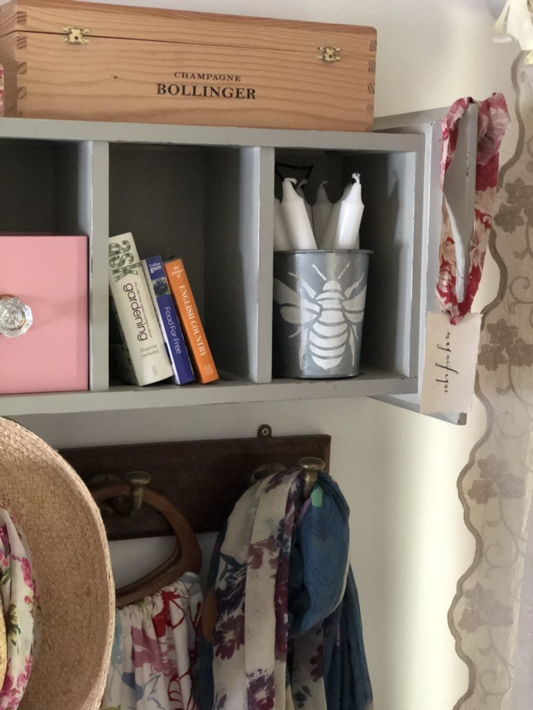 recycled cd storage unit with glass books, pink box and zinc tin stencilled in bee design and white candles