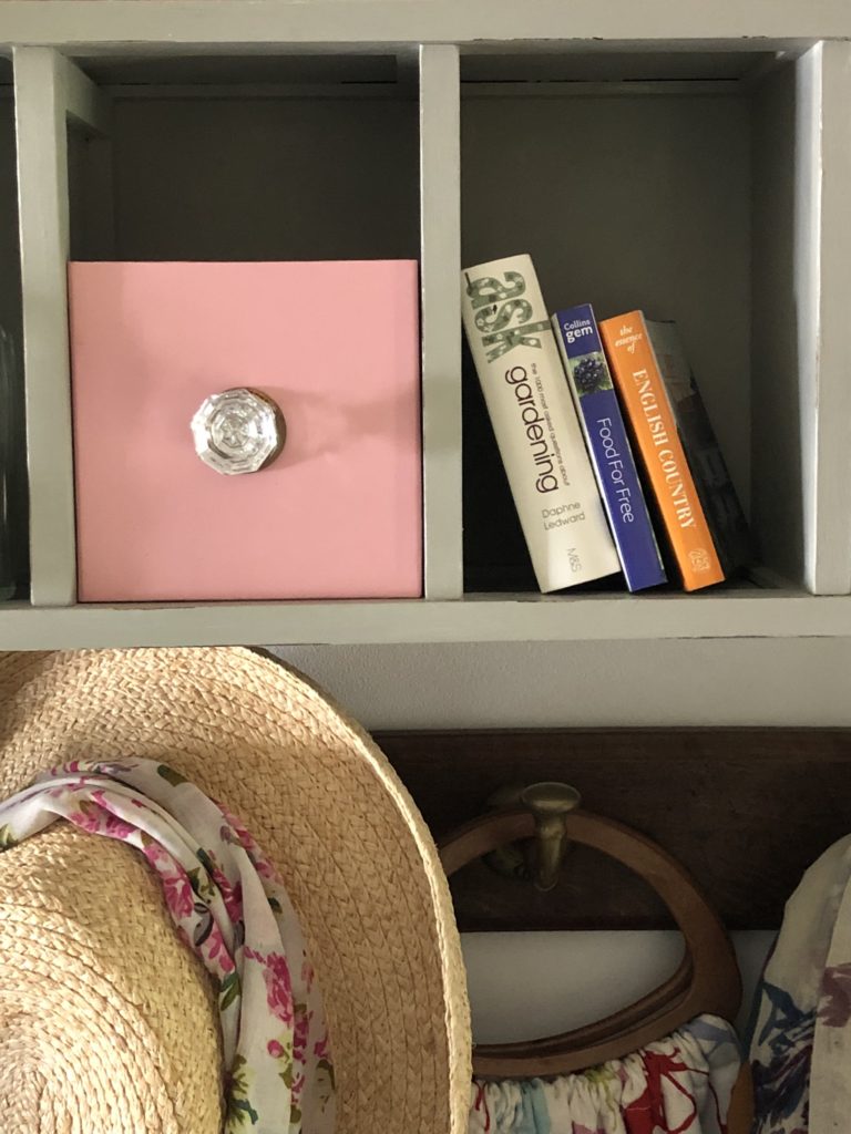 pink box with glass handle next to mini books in recycled cd storage unit