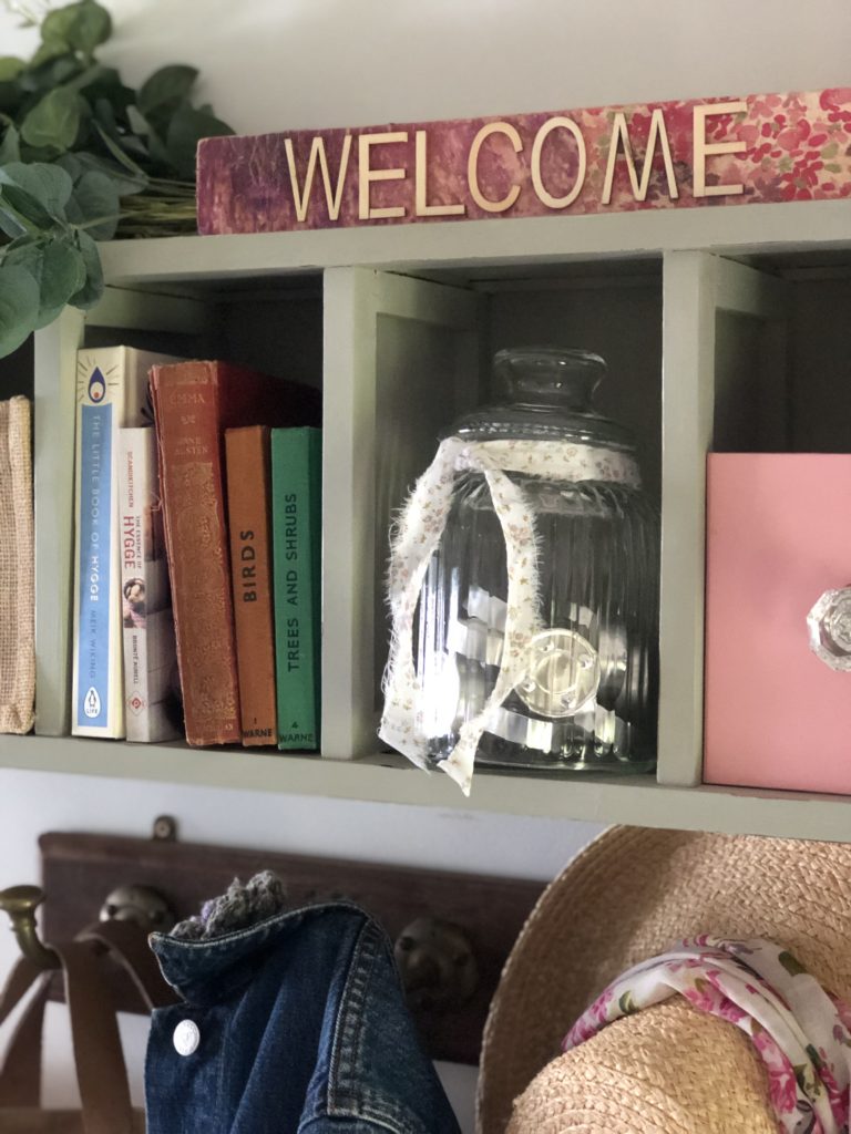 reinvented cd storage unit with books, tealights in glass jar and welcome sign