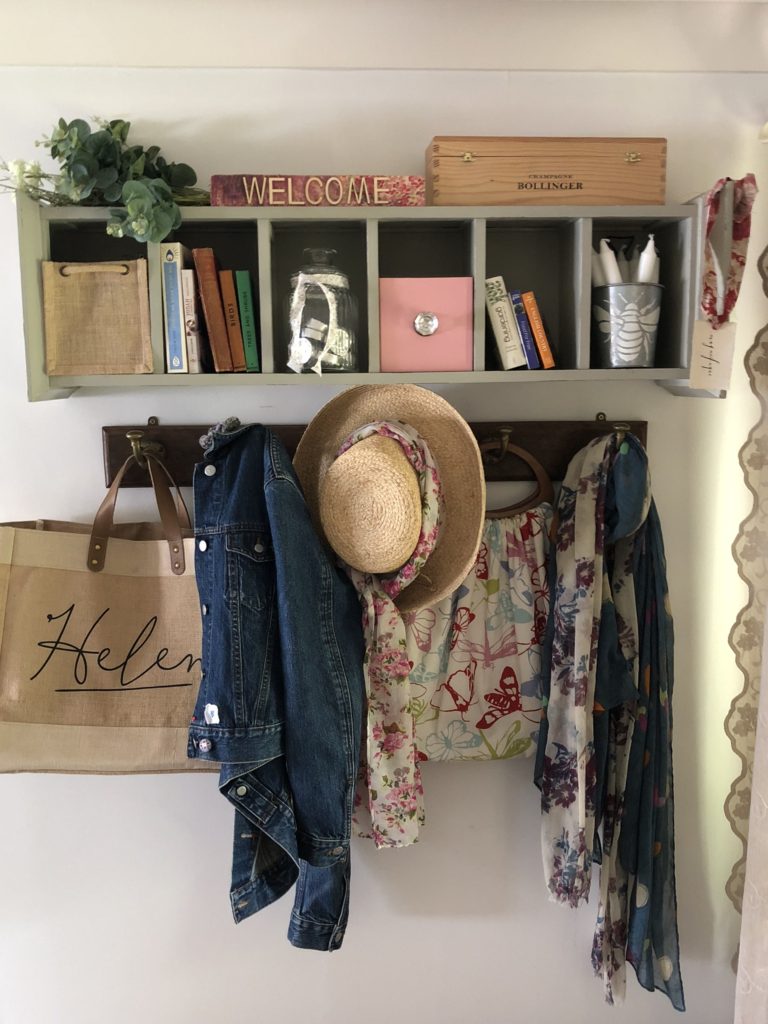 CD storage unit get a new look as a shelf for household pretties and essentials in hallway with hooks and jacket, scarves and bags hanging  beneath