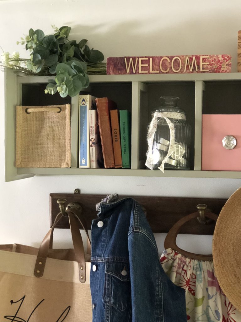 recycled cd storage unit to make a shelf with cubby holes filled with decor and filled coat hooks beneath