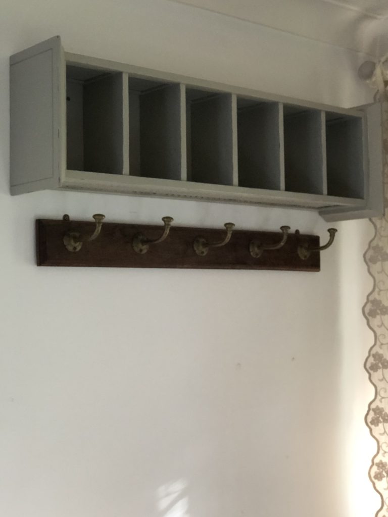 recycled CD storage unit fixed horizontally to wall with hooks beneath