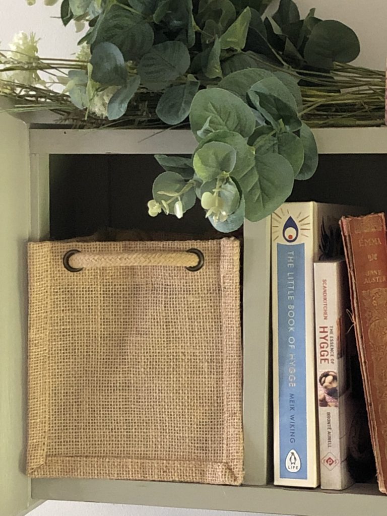 jute box bag on shelf with faux flowers and mini books