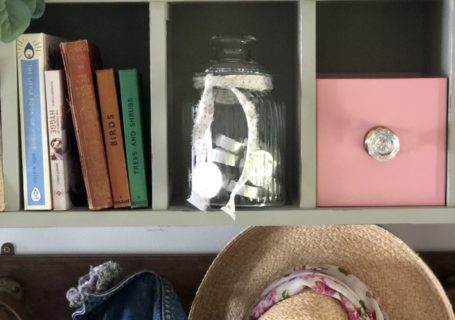 recycled cd storage unit with glass jar, books, pink box an hats and jackets