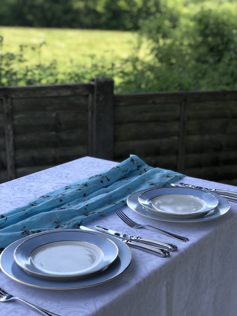 Blue plates and cutlery on white tablecloth create simple table decoration