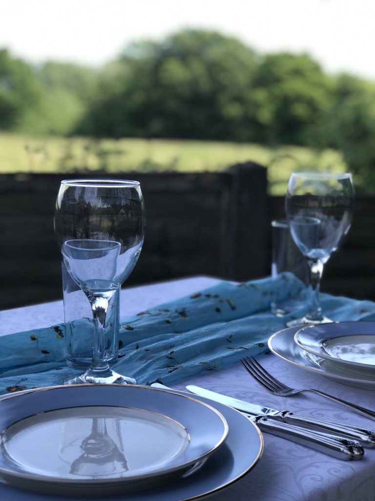 Blue plates and cutlery and glass ware on white tablecloth create simple table decoration