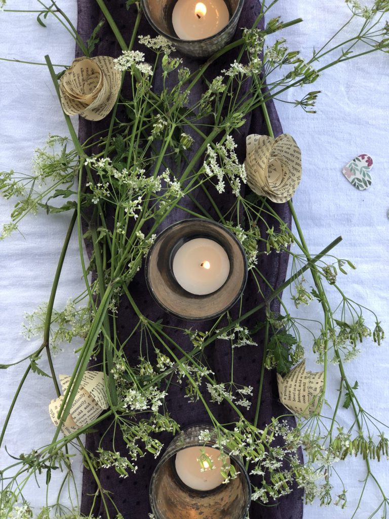 flatlay of purple and green table decoration with candles and cow parsley 