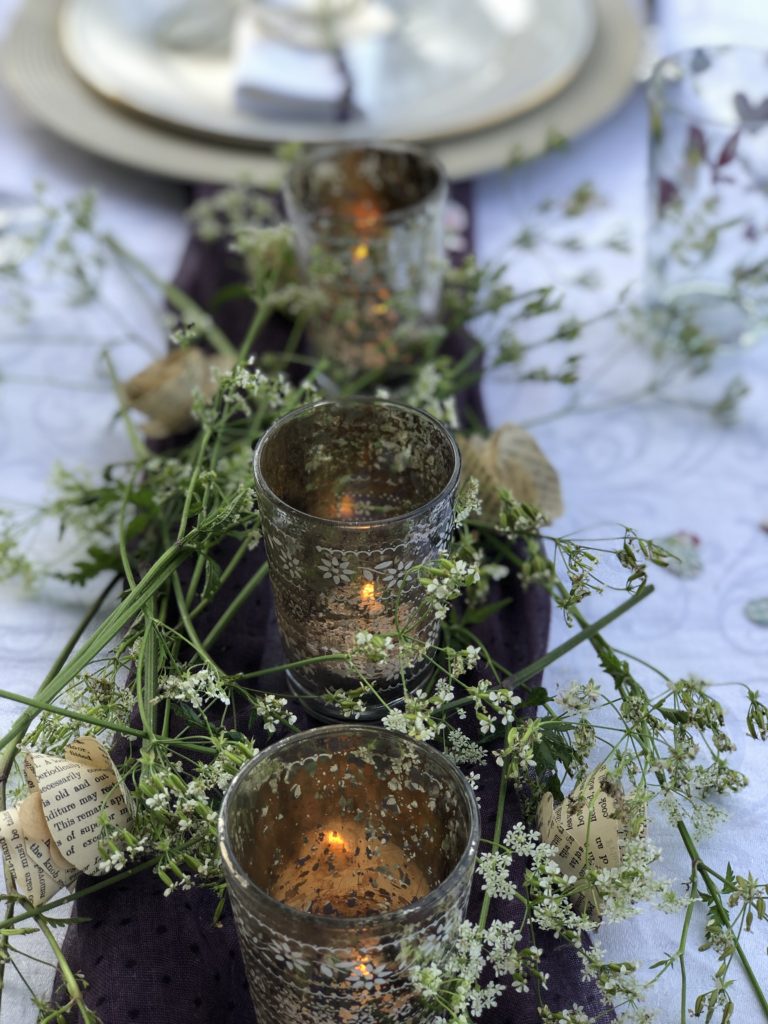 flatlay of purple and green table decoration with candles and cow parsley