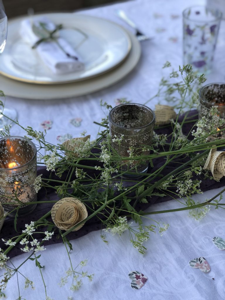 vintage paper roses cow parsley candle votives and purple scarf on top of plain white table coth