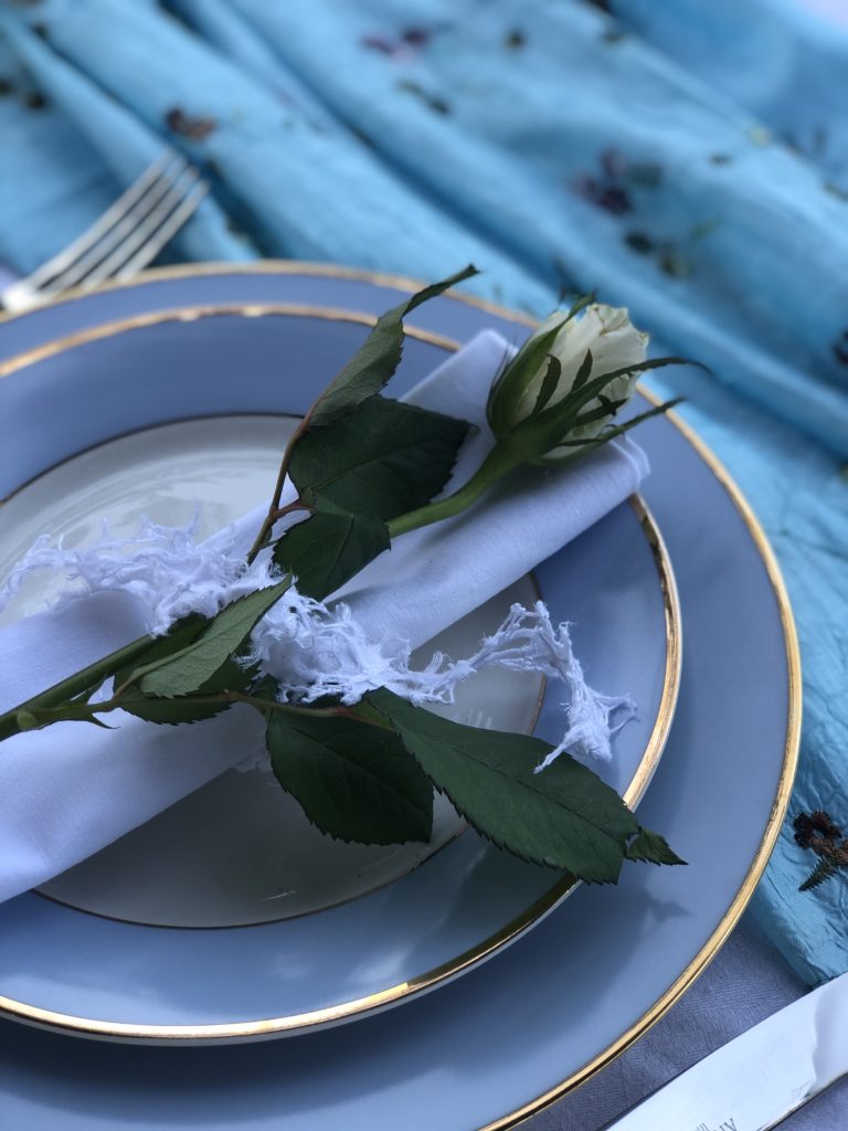 White rose on napkin on blue crockery