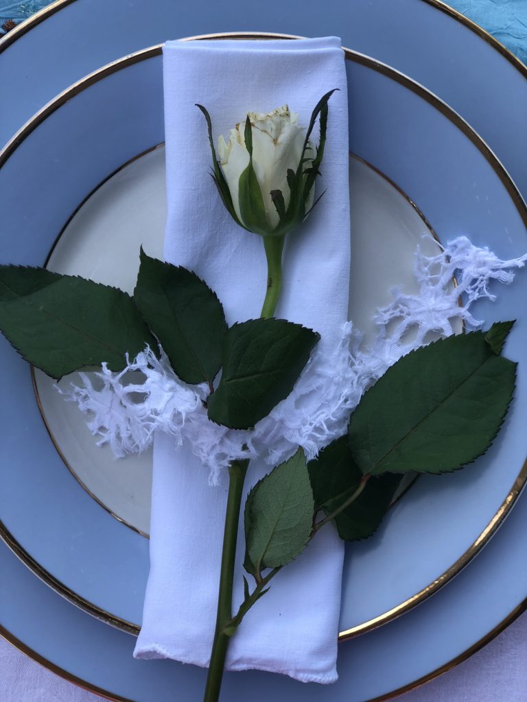 White rose on napkin on blue crockery