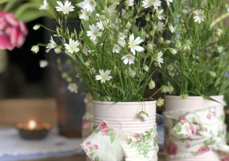 painted pink tin cans with ribbon and flowers for diy summer party decorations