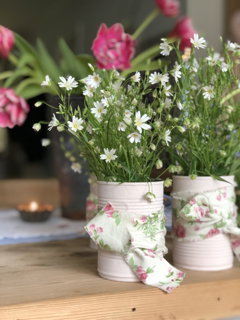 painted pink tin cans with ribbon and flowers for diy summer party decorations