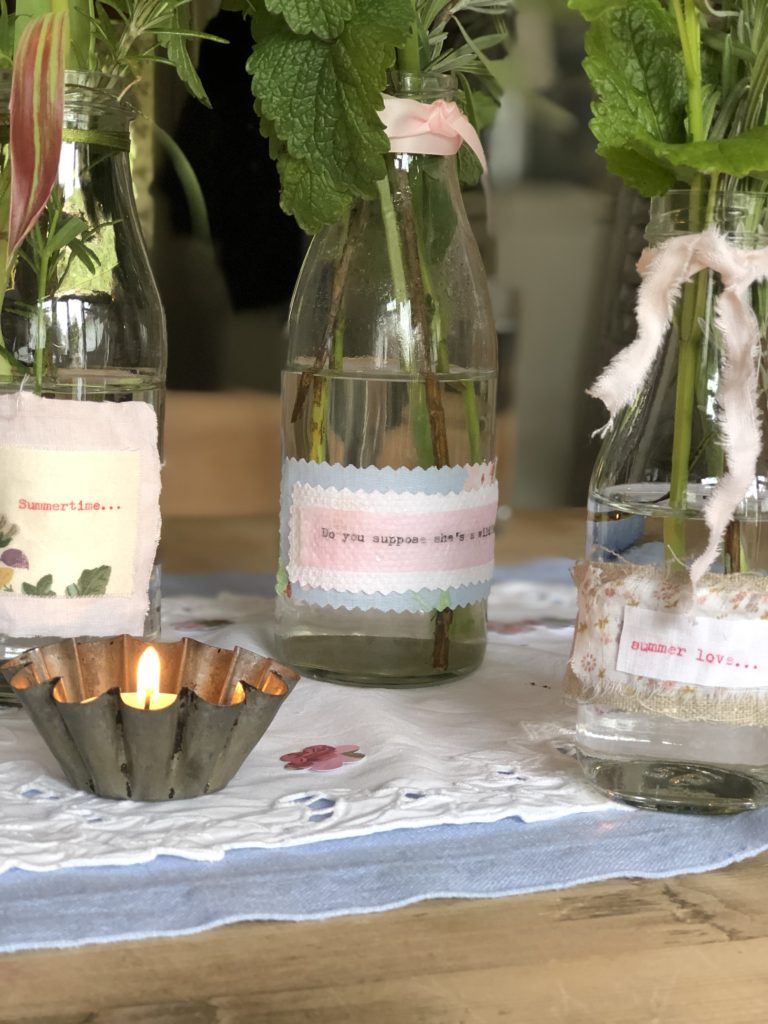 decorative jars and bottles and tin cans hold summer flowers with tealight