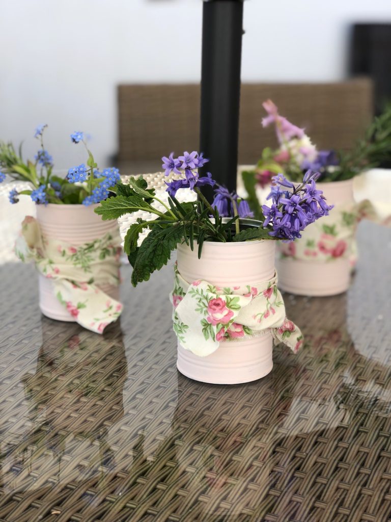 painted pink tin cans with ribbon and flowers for diy summer party decorations