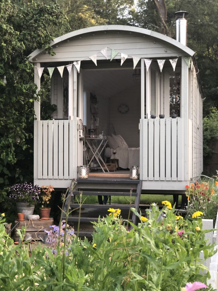 pretty painted shepherds hut and bunting in summer garden