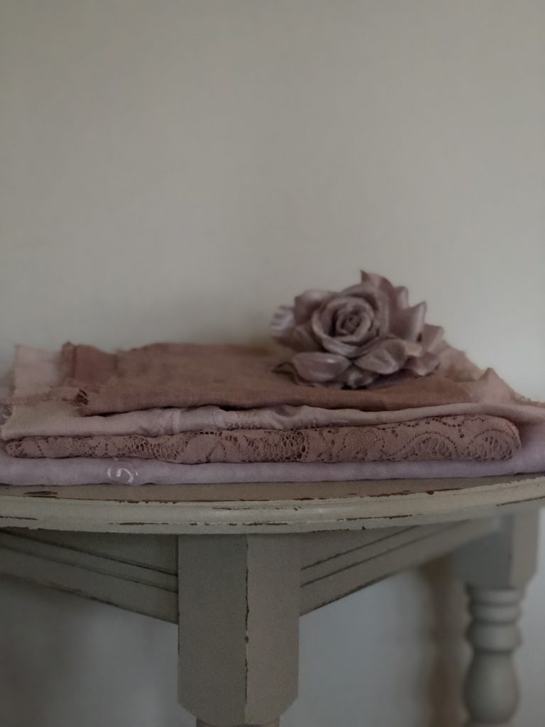 selection of avocado dyed vintage fabrics on table with silk pink rose