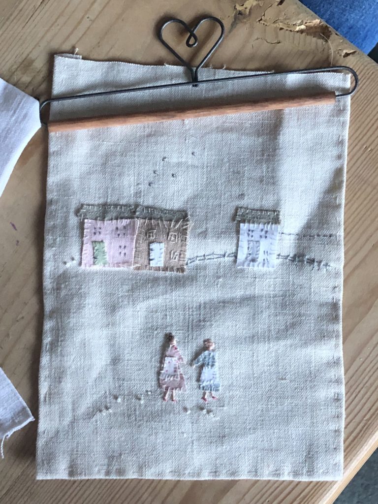 hand stitched sampler of ladies, cottages and washing