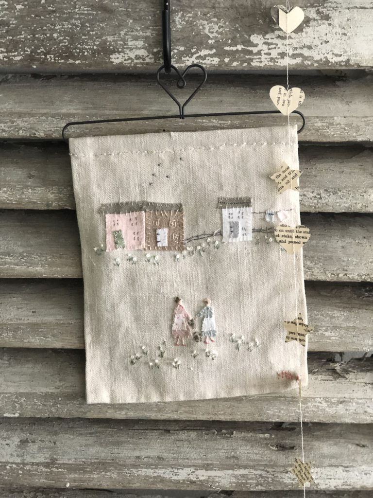 hand stitched sampler of ladies, cottages and washing