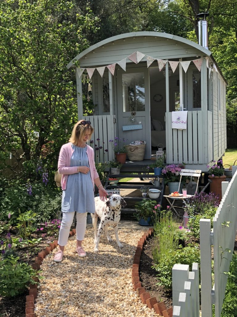 blonde lady with dalmatian dog in front of pretty shepherds hut with bunting