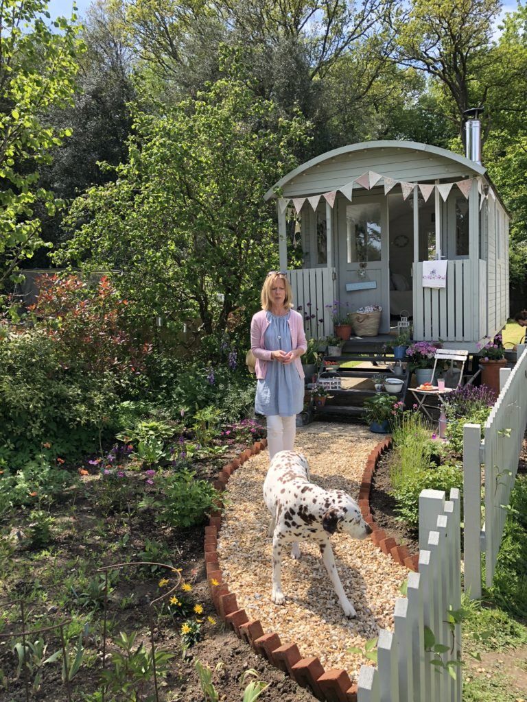 blonde lady with dalmatian dog in front of pretty shepherds hut with bunting