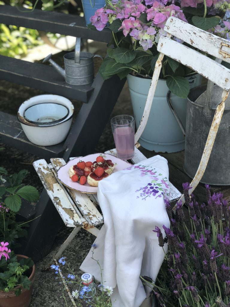 scones and strawberries on chipped garden chair with tablecloth for Period iIving Magazine photo shoot