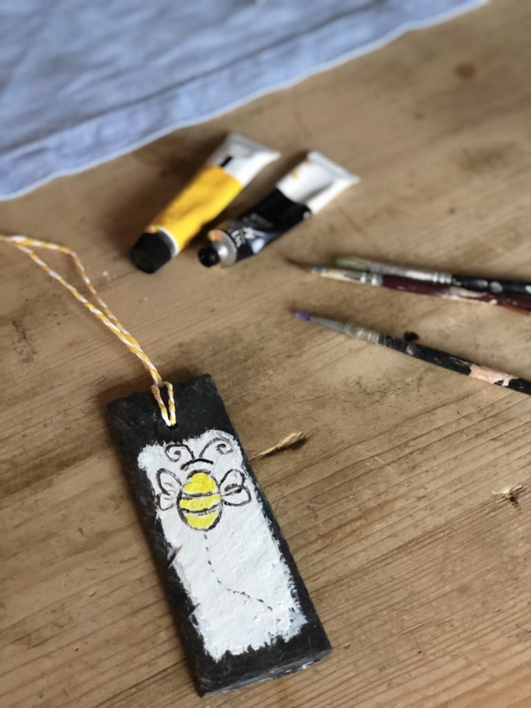 painting a bee onto a slate plant maker