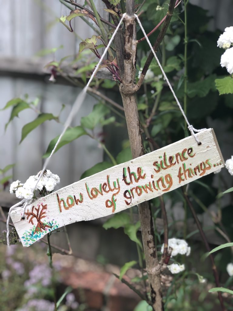 wooden garden sign hanging in the trees