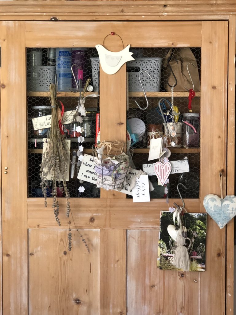 Front view of pine craft cupboard adorned with trinkets