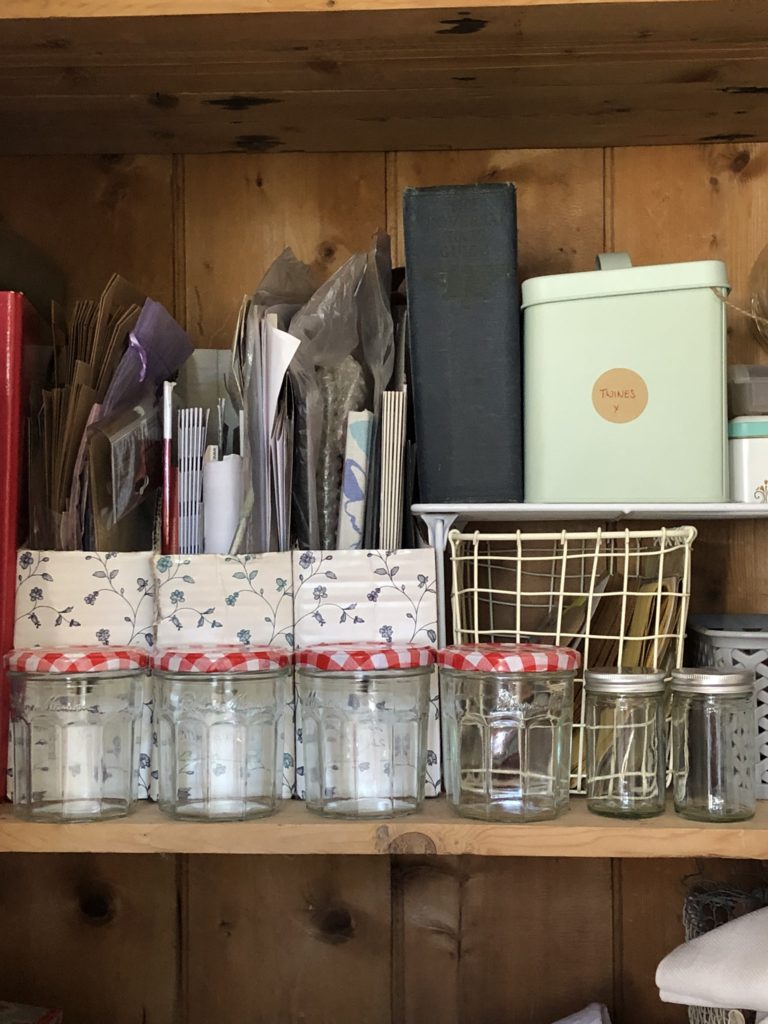 variety of glass storage jars on shelf in craft cupboard