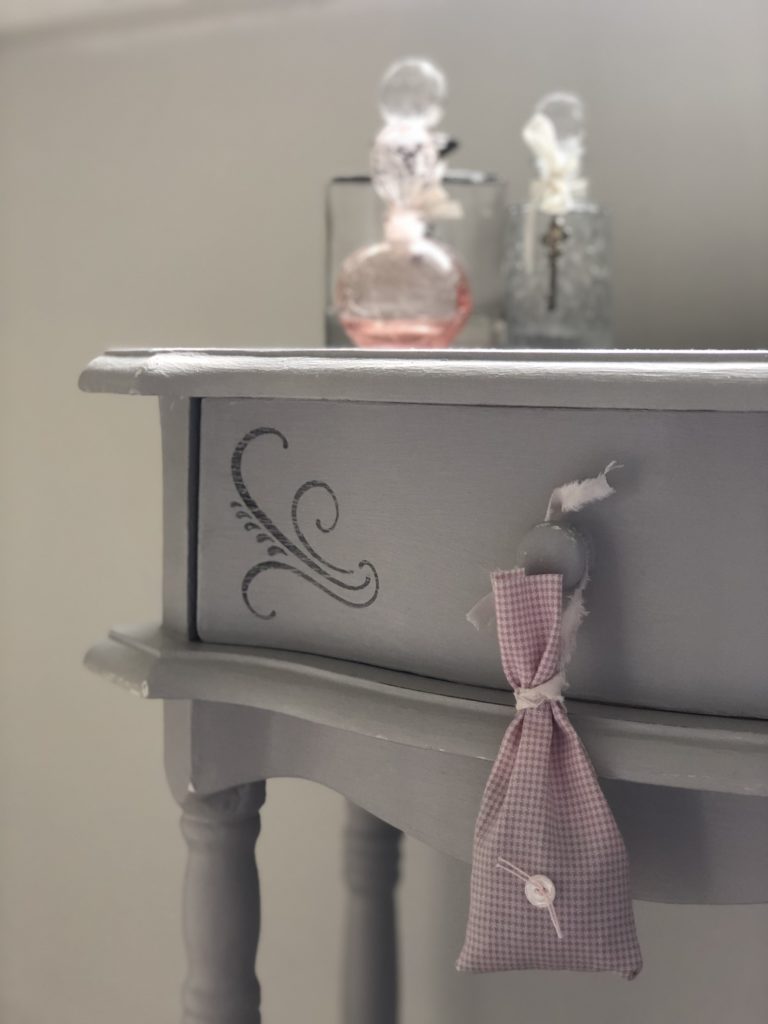 pink gingham lavender bag on painted cabinet with glass bottles