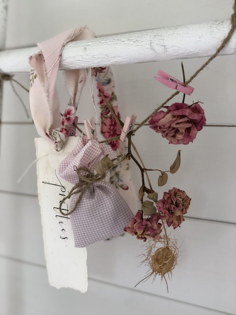 pink lavender bag hanging on white ladder with dried flowers and paper label