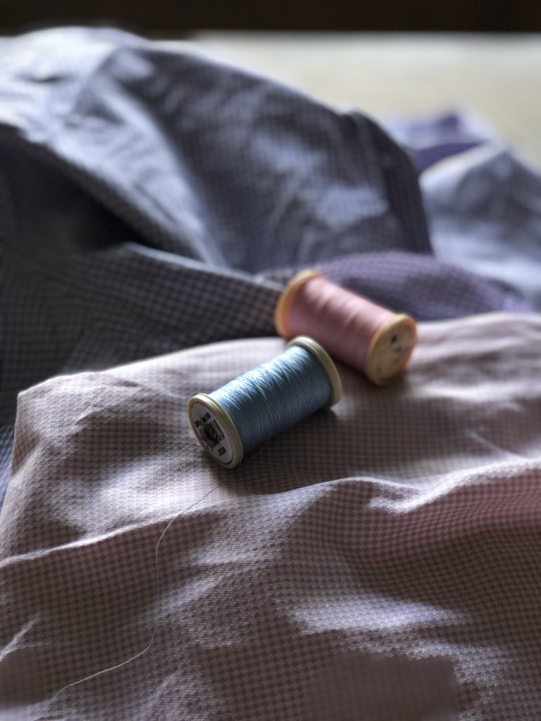 blue and pink cotton reels on pink and purple gingham fabric