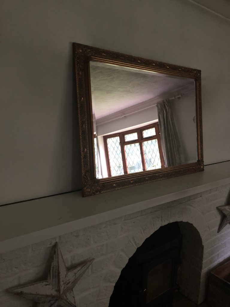 bare mantlepiece with large brass mirror