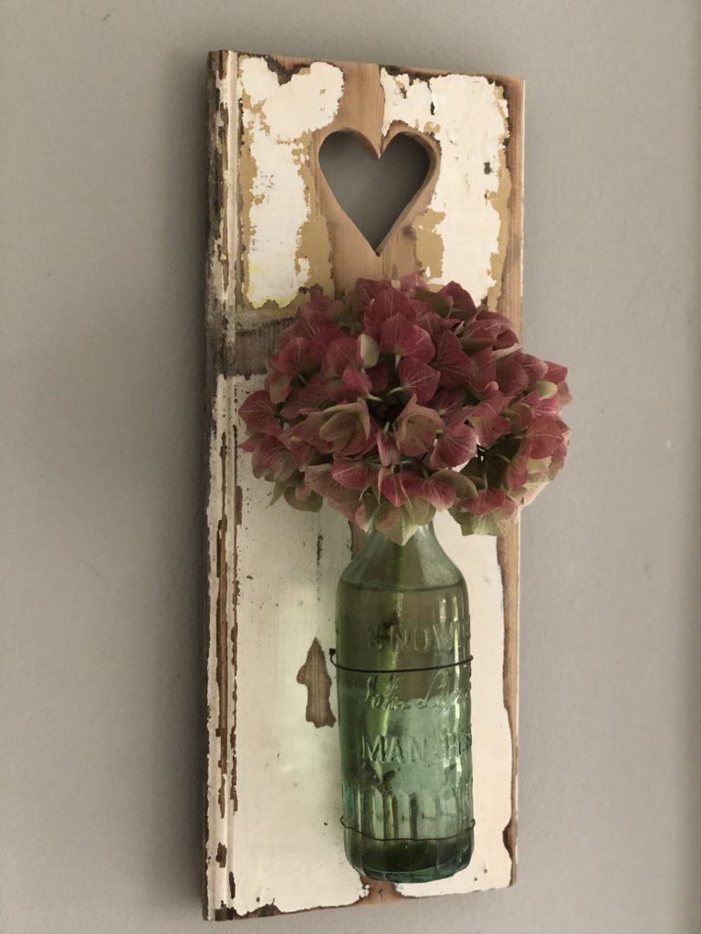 chippy white wood with green bottle and hydrangea on wall