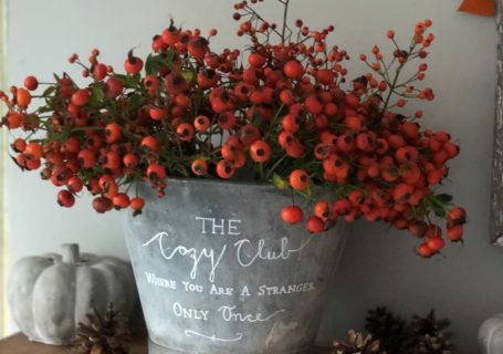 zinc bucket with painted message full of orange rosehips on wooden mantle