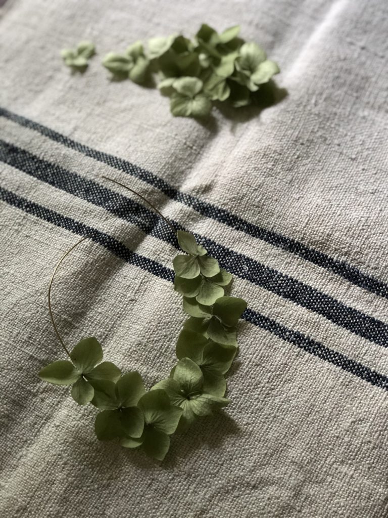 sticking green hydrangea petals to gold circle of wire