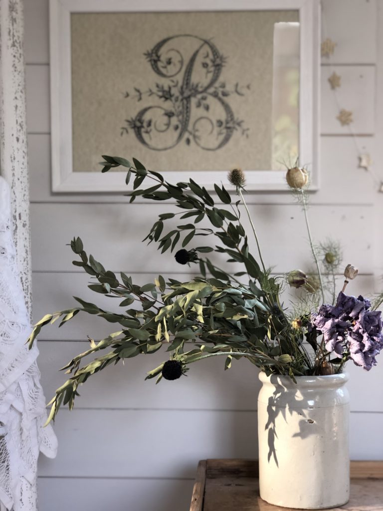 dried flowers against whitewashed wall and B print