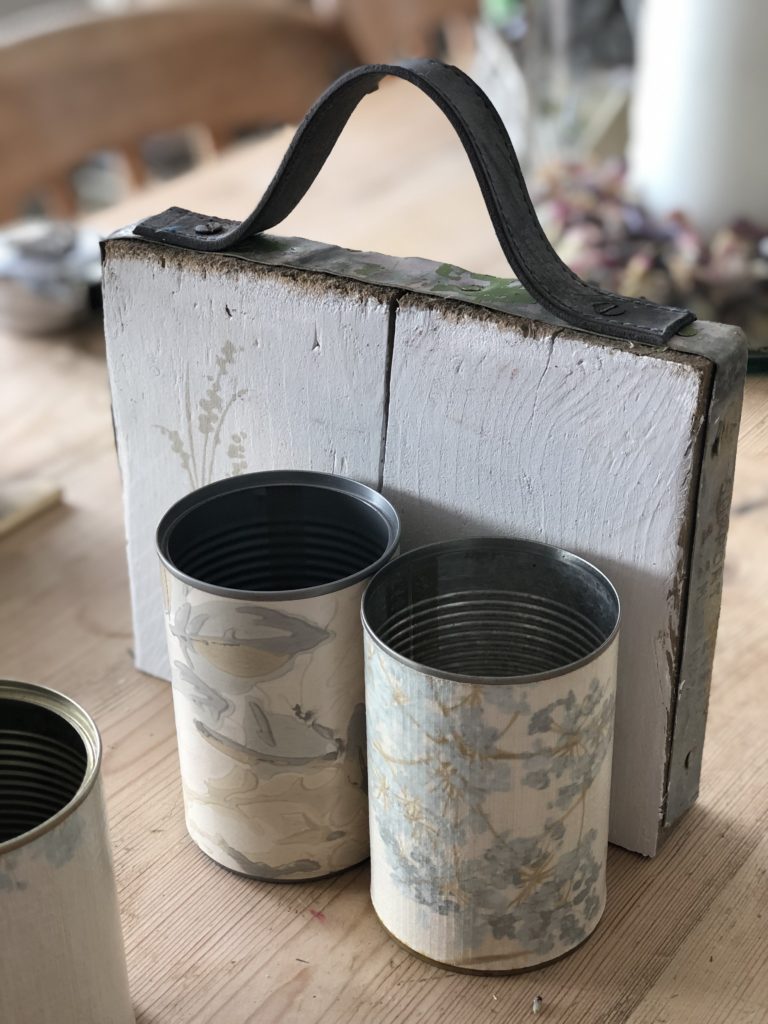 wallpapered tin cans on white painted board with leather handle